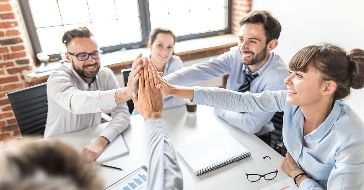 Group of five people in dress shirts giving a high five together