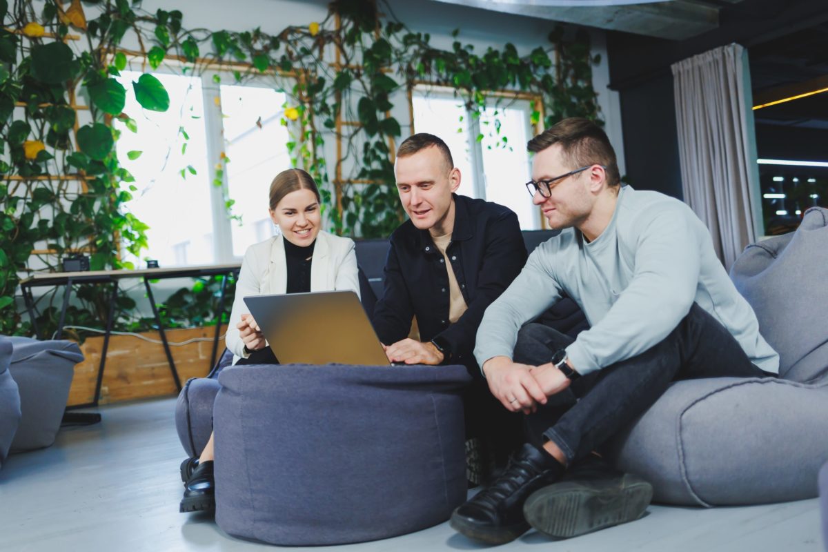 Group of workers looking at a computer on an office couch