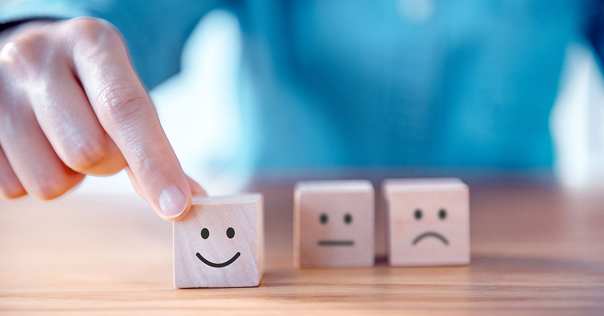 Hand moving wooden blocks that have smiley emojis on them