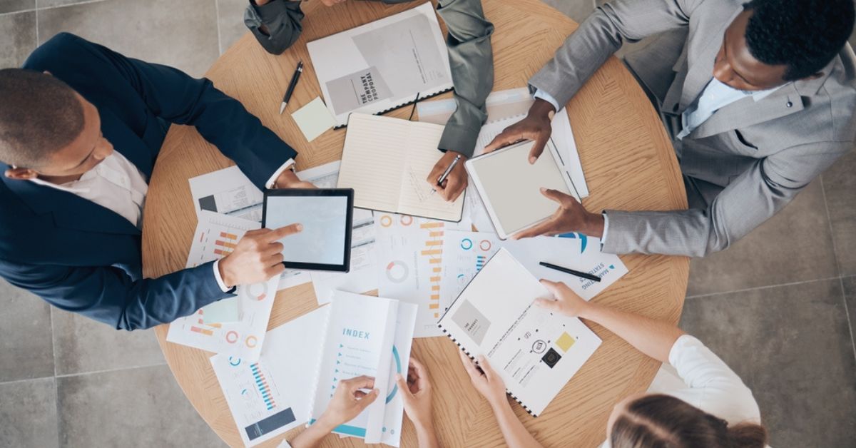People looking at a pile of charts and graphs on a table